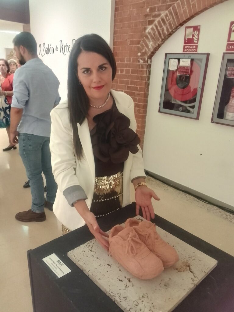 Carmen Belén Serrano serrano, junto a su escultura Miss Zapatillas terracota y piedra
