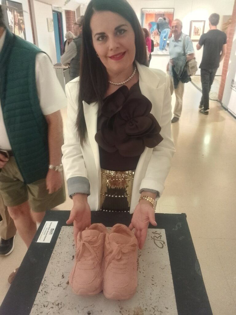 Carmen Belén Serrano serrano, junto a su escultura Miss Zapatillas terracota y piedra